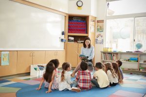 small class sizes in school kids sitting on the floor gathered around teacher walton academy